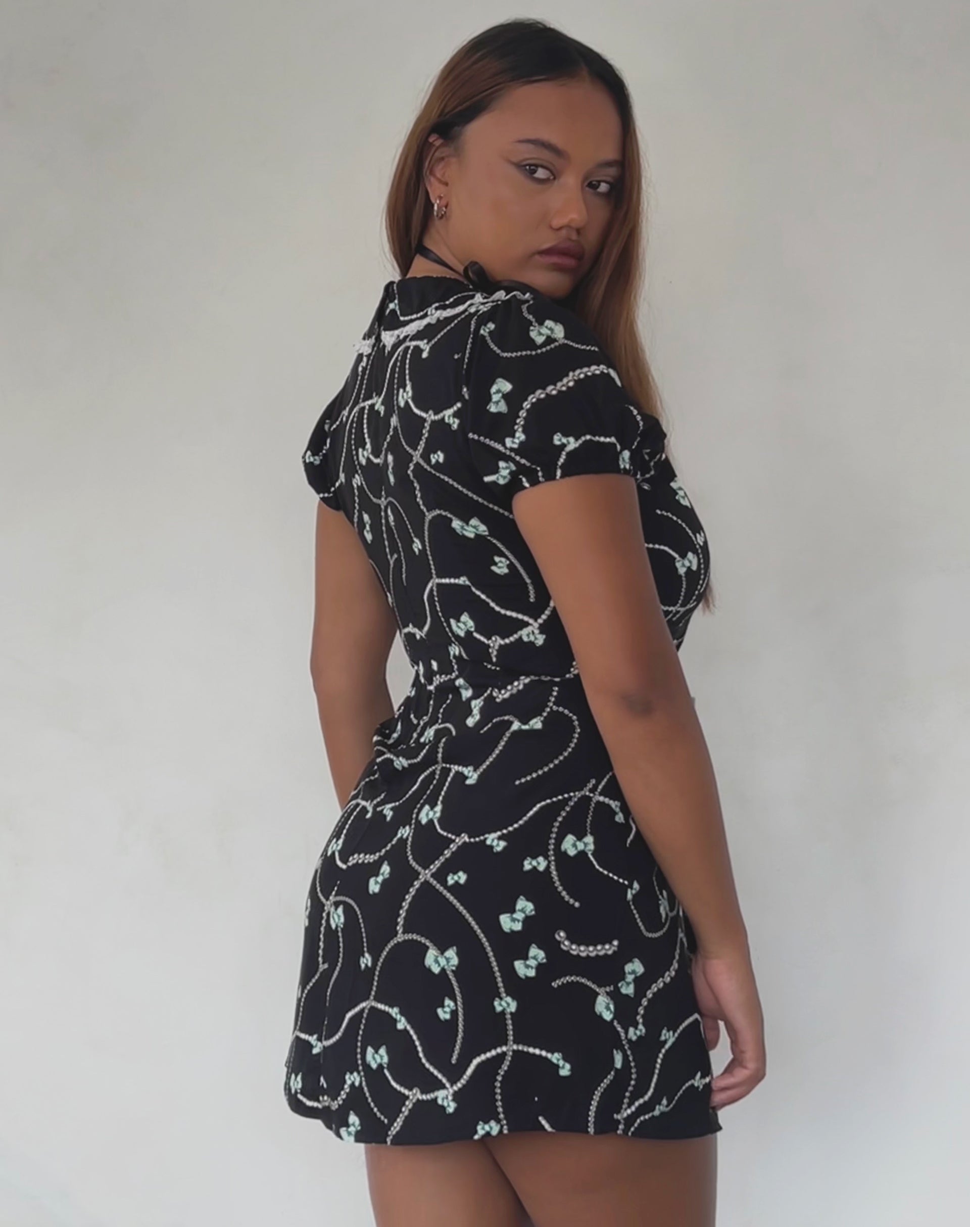 Afbeelding van Sulani Mini jurk in zwart met parel en strikprint